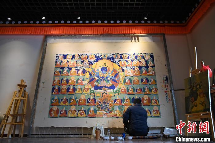 图为青年画师旦正嘉在唐卡小镇一画室内席地而坐绘制巨幅唐卡。作为唐卡文化的传承人，交巴加布致力于培养新一代唐卡画师，将自己的艺术经验和技艺毫无保留地传授给学生们。自1997年以来，交巴加布收徒数十名，传授唐卡画法。九美旦增 摄

